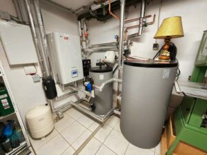 Moderne Wärmepumpe mit Warmwasserspeicher im Heizungsraum eines Wohnhauses