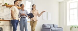 Maklerin zeigt einem Paar eine helle Wohnung bei der Besichtigung
